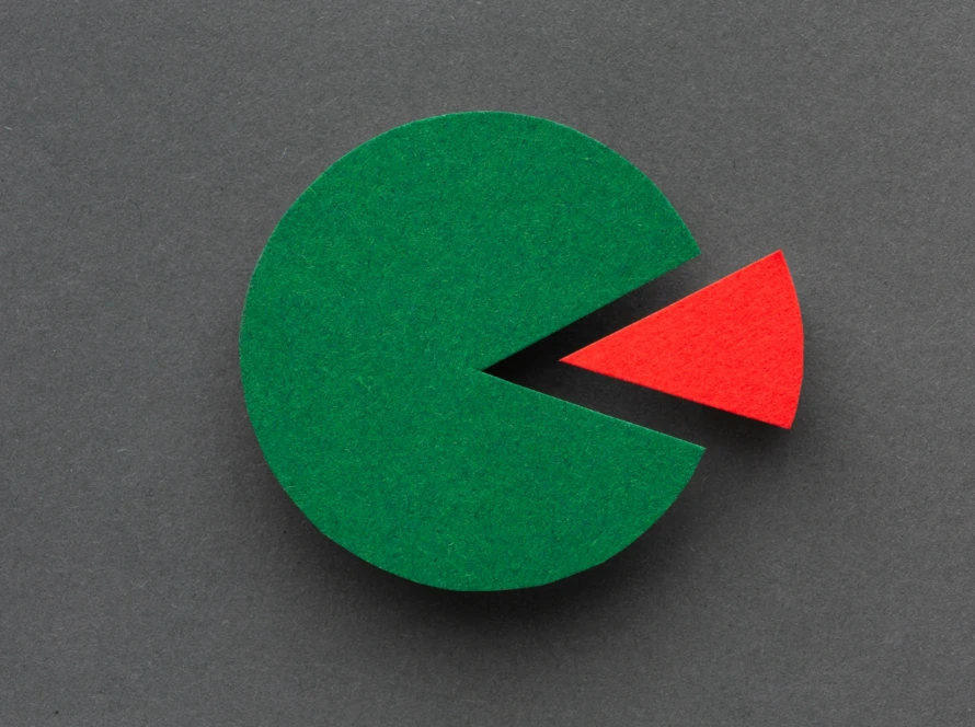 Paper pie chart featuring a large green circle and a small detached red slice on a dark-grey background, symbolising market-share opportunity.