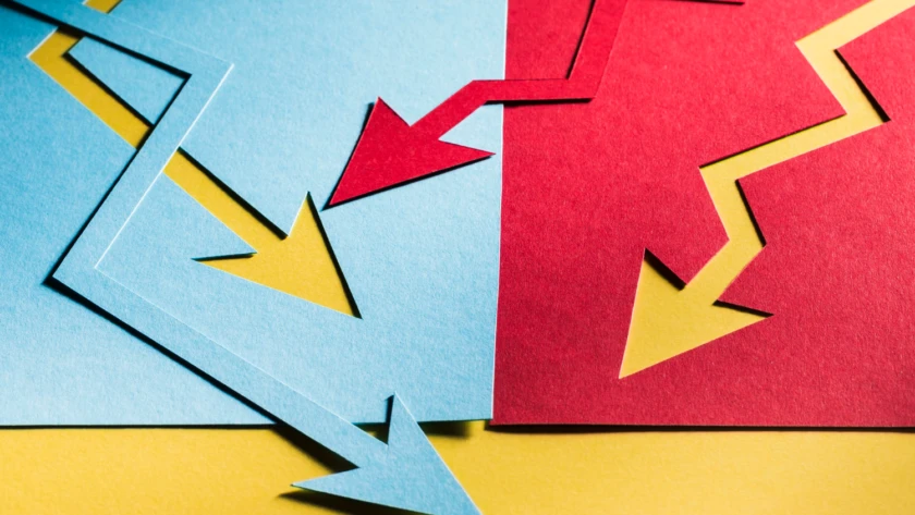 Blue and red zig-zag paper arrows pointing down on a yellow background, illustrating diverging trends in agile sprint planning.