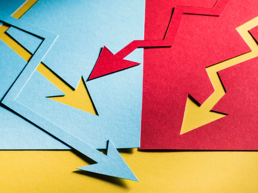 Blue and red zig-zag paper arrows pointing down on a yellow background, illustrating diverging trends in agile sprint planning.